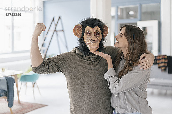 Man wearing chimpanzee mask  flexing muscles  woman petting him