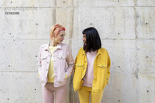 Two alternative friends having fun  wearing yellow and pink jeans clothes  face to face