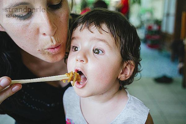 Thailand  Chiang Mai  Mother feeding her daughter with Pad Thai  using chopsticks