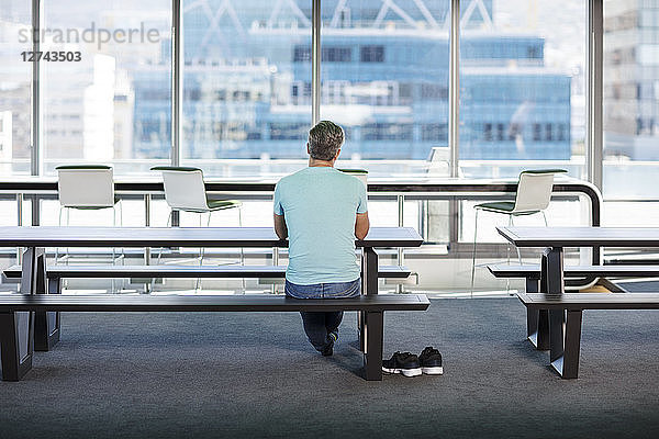 Man working in modern office  sitting on bench  rear view