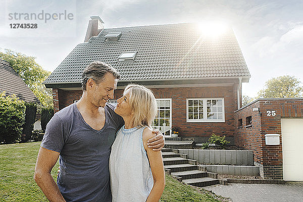 Smiling mature couple embracing in garden of their home