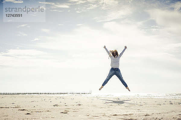 Happy woman having fun at the beach  jumping in the air