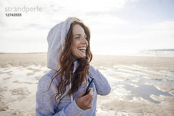 Woman having fun on a windy beach  wearing hood