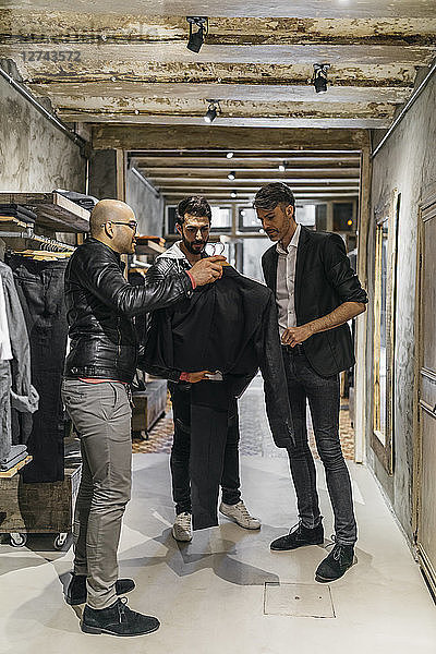 Designer and stylist in modern menswear shop offering new collection to man