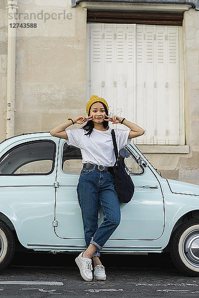 Portrait of young woman standing at small car