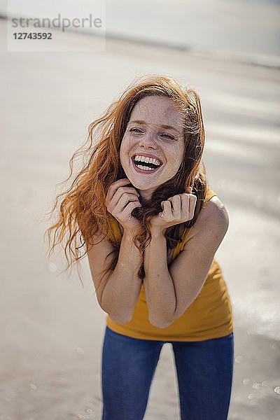Redheaded woman  laughing happily on the beach