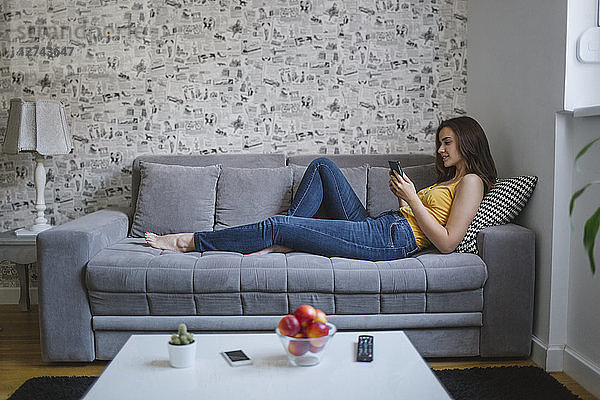 Woman on couch in the living room reading e-book