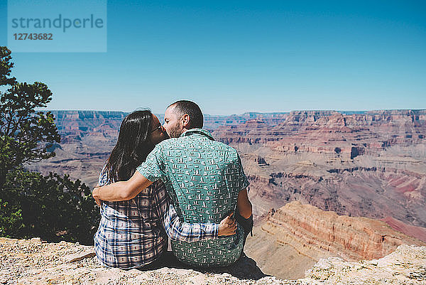 USA  Arizona  Grand Canyon National Park  back view of kissing couple sitting side by side