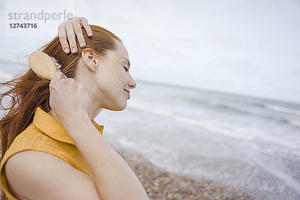 Woman using hair brush at the sea
