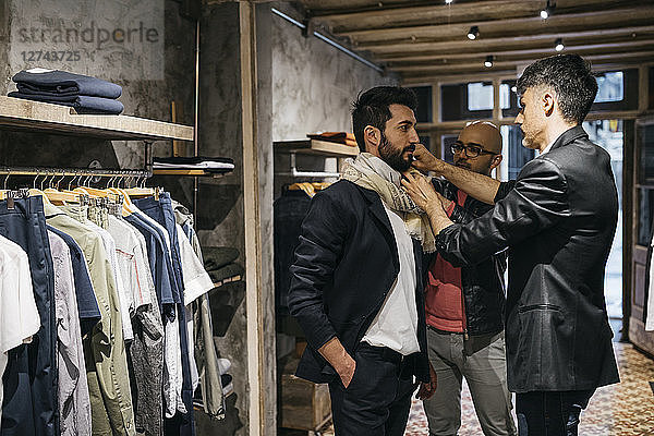Two men working on new stylish look for handsome man in showroom