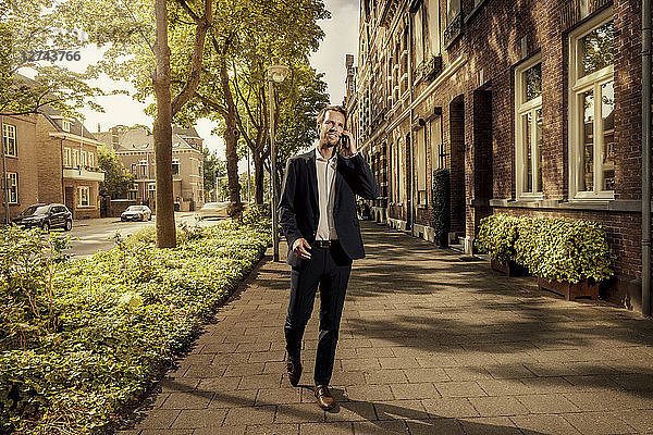 Netherlands  Venlo  businessman on cell phone walking on pavement