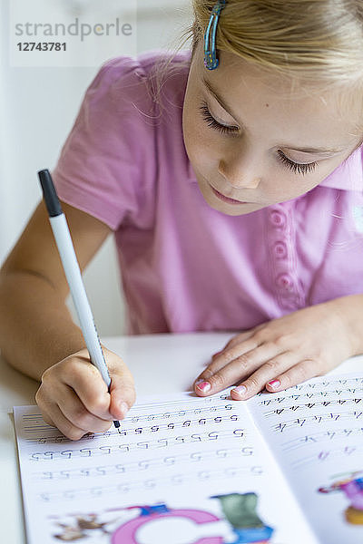 Little girl writing numbers in exercise book