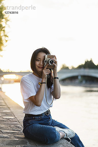 France  Paris  portrait of young woman with camera at river Seine at sunset