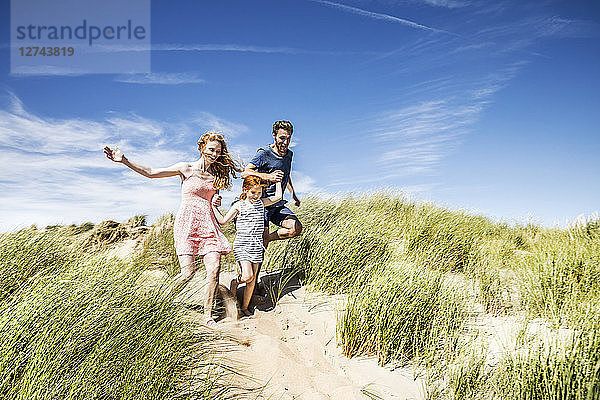 Netherlands  Zandvoort  happy family with daughter running in beach dunes