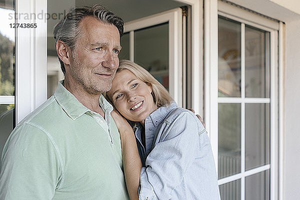 Portrait of smiling mature couple at French window