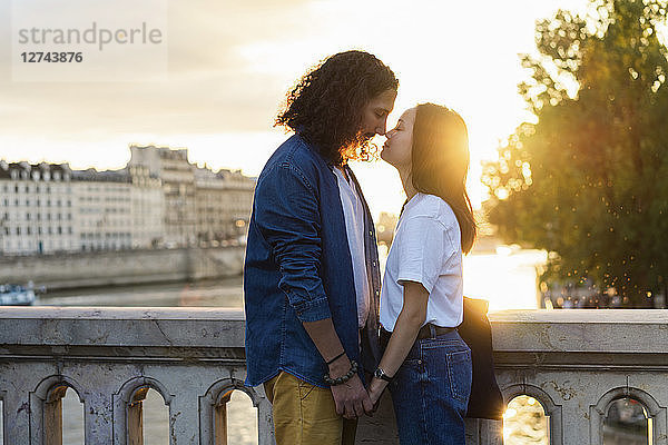 France  Paris  affectionate young couple at river Seine at sunset