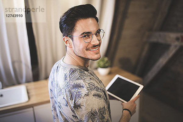 Portrait of smiling young man using tablet at home