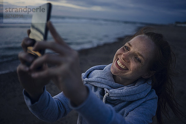 Woman using smartphone on the beach at sunset