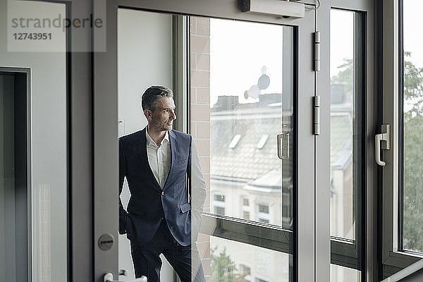 Businessman in office looking out of window