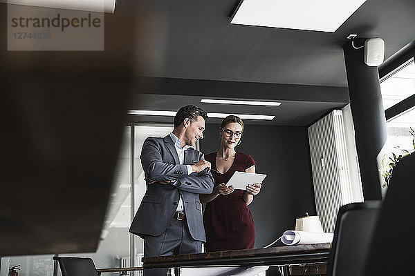 Businesswoman and businessman sharing tablet in office