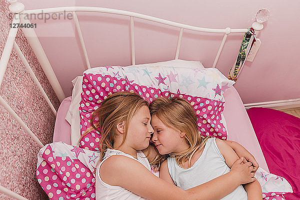 Two little sisters resting on bed