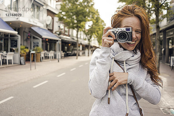 Redheaded woman using analogue camera
