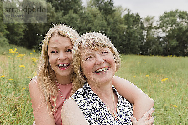 Portrait of mother and adult daughter having fun on a meadow