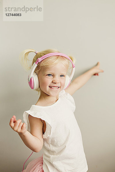 Portrait of blond little girl with headphones dancing