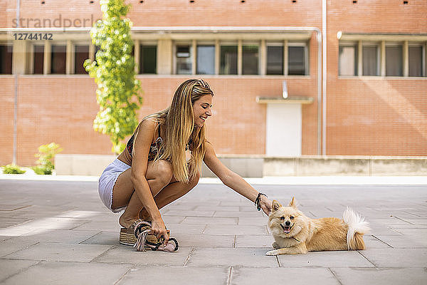 Pretty young woman smiling  caressing a pomeranian