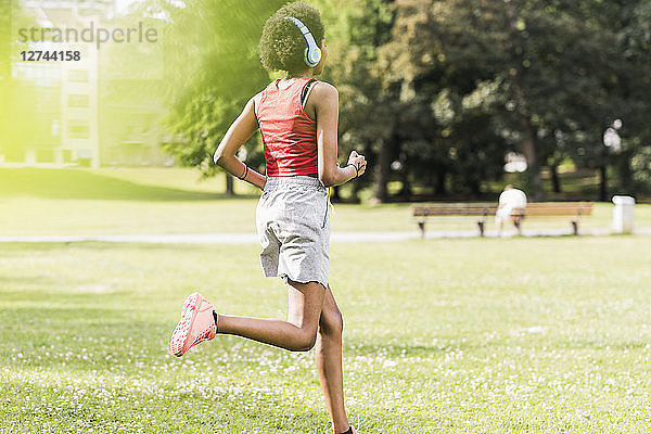 Young woman with headphones running in park