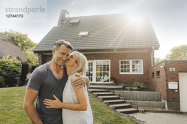 Portrait of smiling mature couple embracing in garden of their home