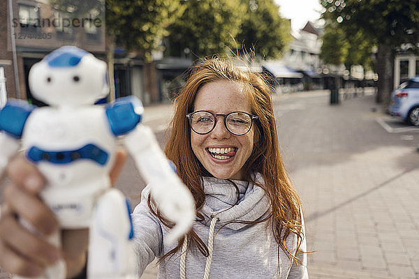 Redheaded woman showing toy robot