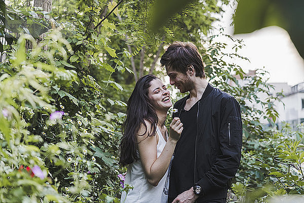 Happy young couple standing in shrubbery