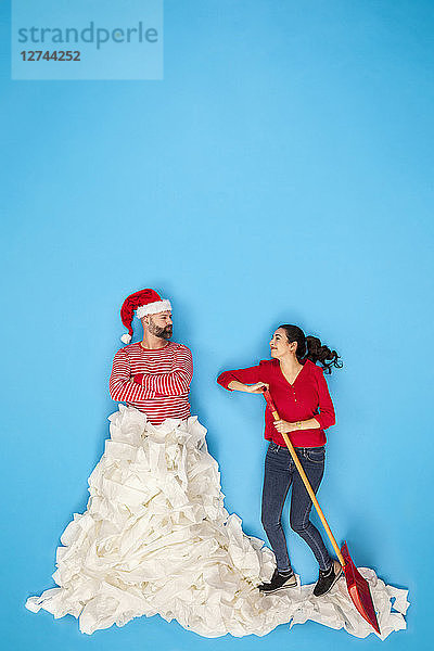 Couple shoveling snow  man wearing Santa hat