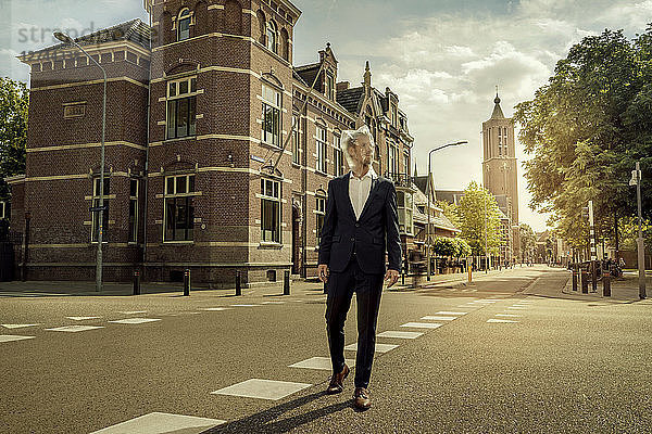 Netherlands  Venlo  businessman walking on a street with plastic bag over his head