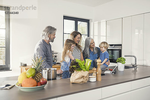 Grandparents with grandchildren and their mother standing in kitchen