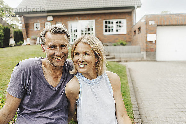 Portrait of smiling mature couple sitting in garden of their home