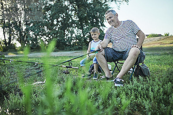 Grandfather and grandson fishing together at lakeshore