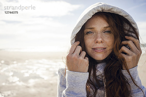 Woman wearing hood on a windy beach