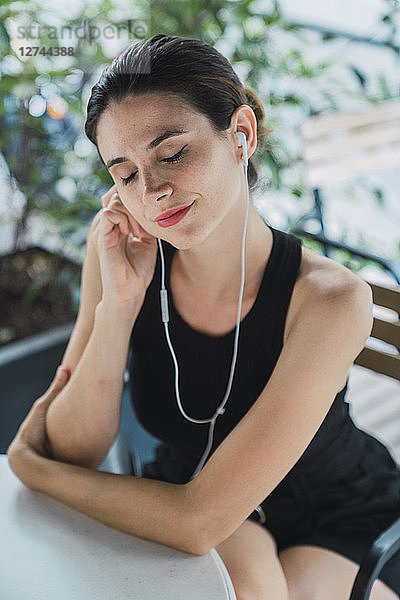 Young businesswoman sitting in coffee shop  taking a break  listening music