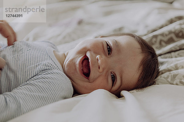 Happy baby  lying on bed  laughing