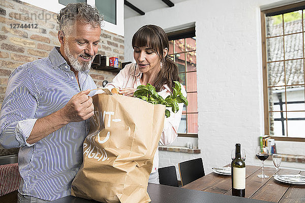 Mature man bringing grocery bag full of purchase to the kitchen