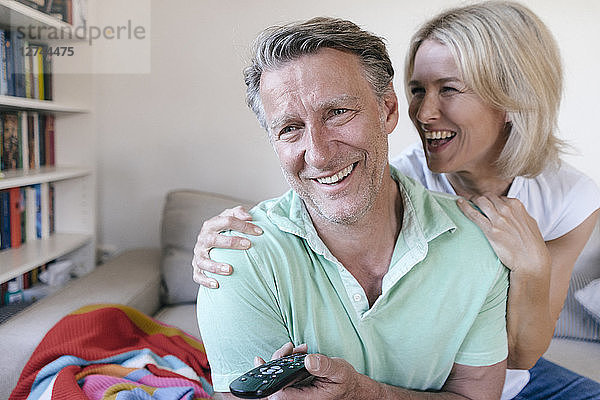 Happy mature couple at home watching Tv