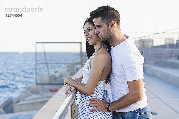 Happy young couple standing by the sea