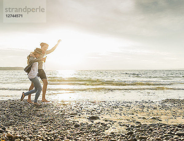 Happy young couple walking on the beach at sunset