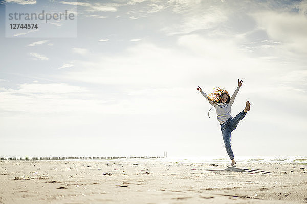 Happy woman having fun at the beach  dancing in the sand