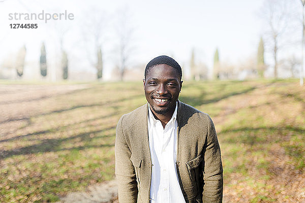 Portrait ogf young man in park  wearing jacket  smiling