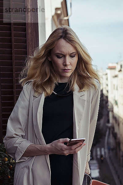 Portrait of blond young woman looking at cell phone