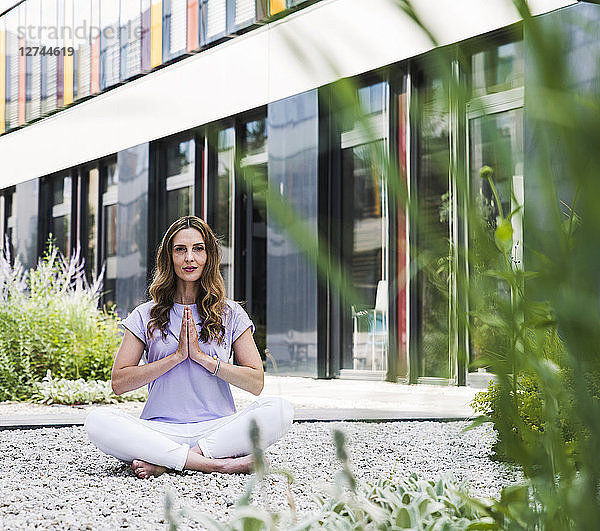 Woman practicing yoga in garden outsde office building