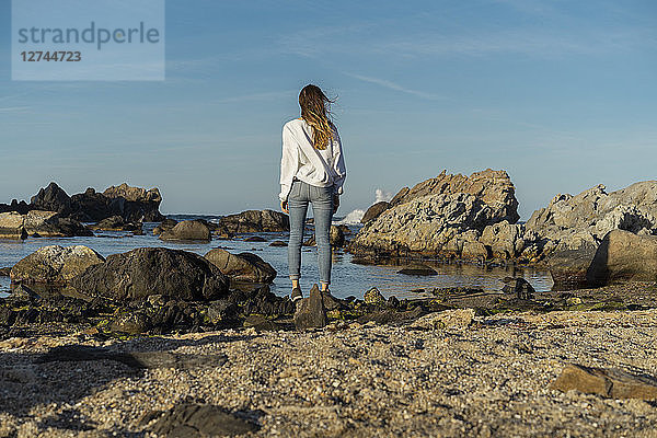Woman looking sitting on rocks  looking at the sea